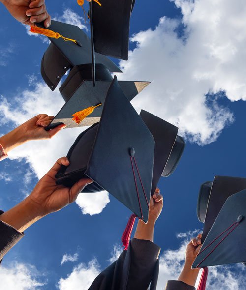 Image of graduation caps against a partly cloudy sky